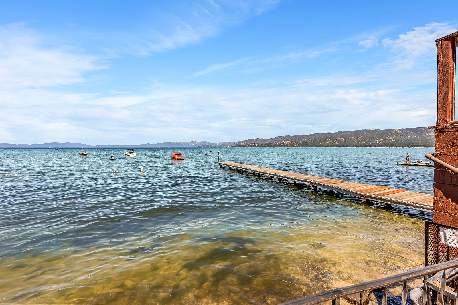 The Beachcomber Inn's private dock reaching into Lake Tahoe, with boats on the mooring buoys beyond it